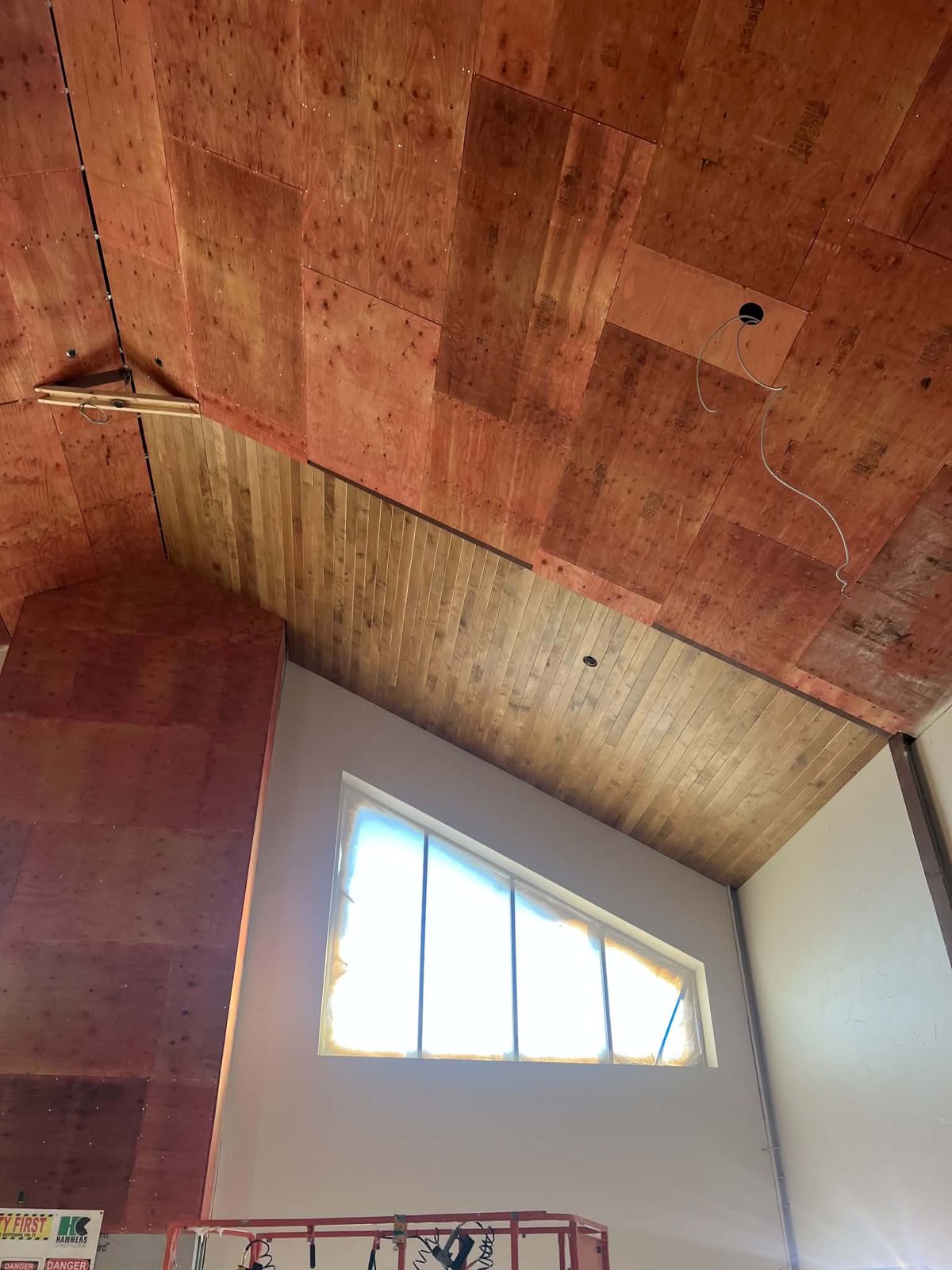 Before: vaulted great room with a plywood ceiling and plywood-wrapped chimney