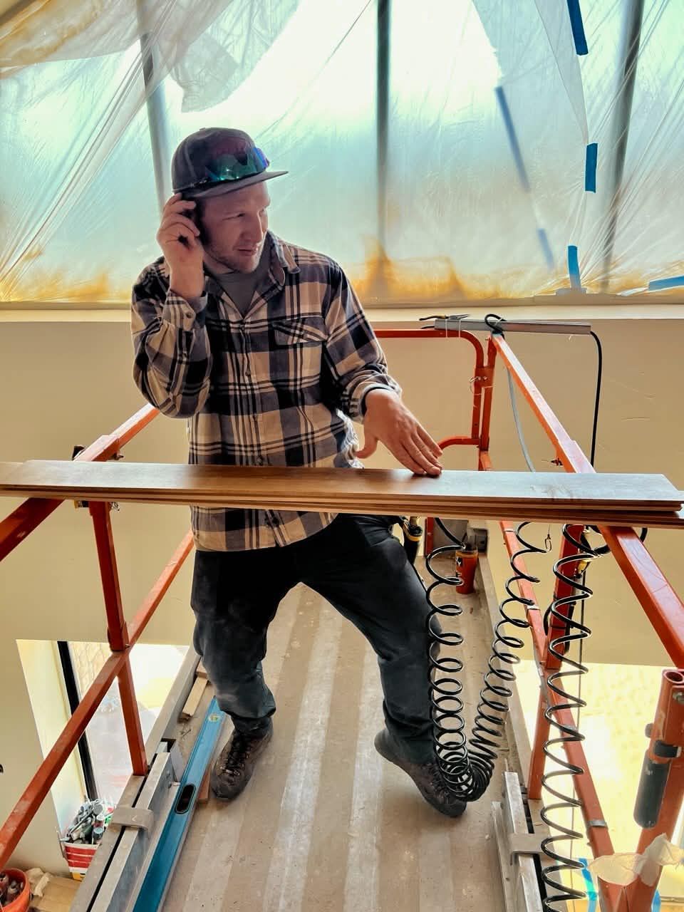 Carpenter in a hard hat on a lift installing ceiling planks