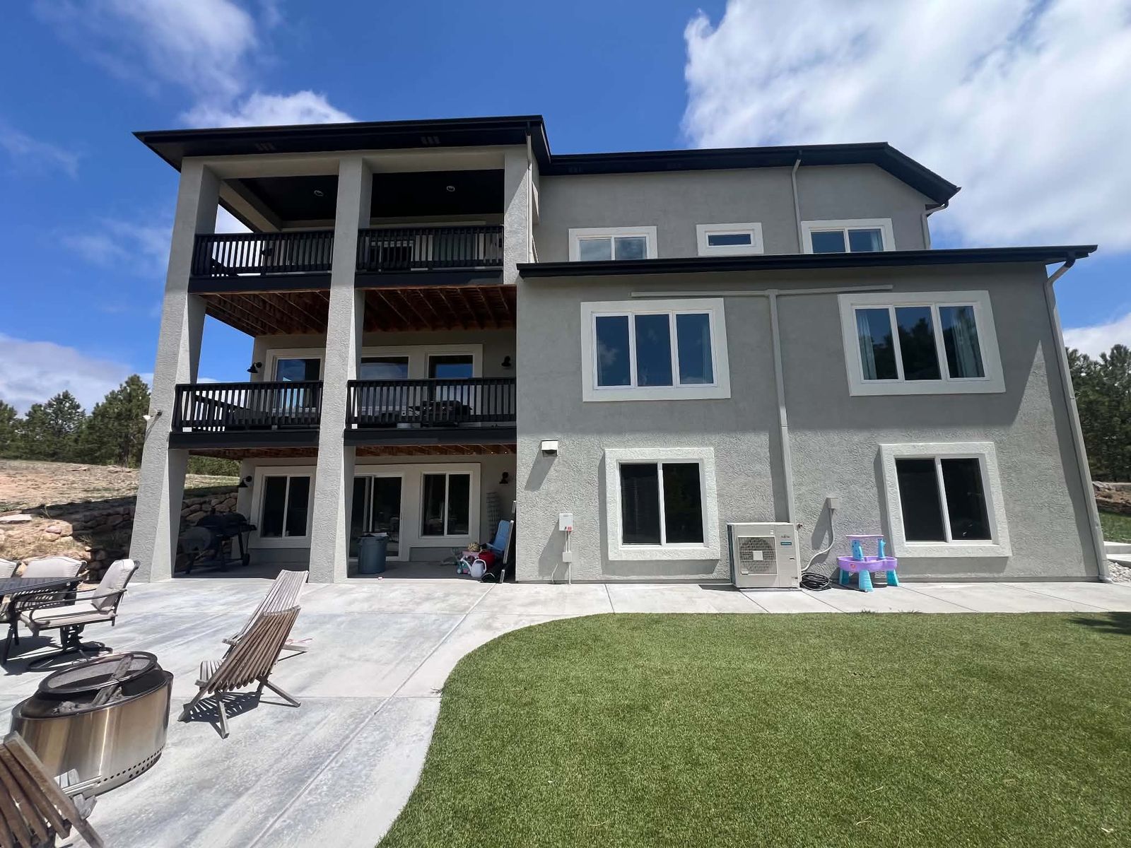 Stacked decks across the back of a three-story home with a stone patio and lawn